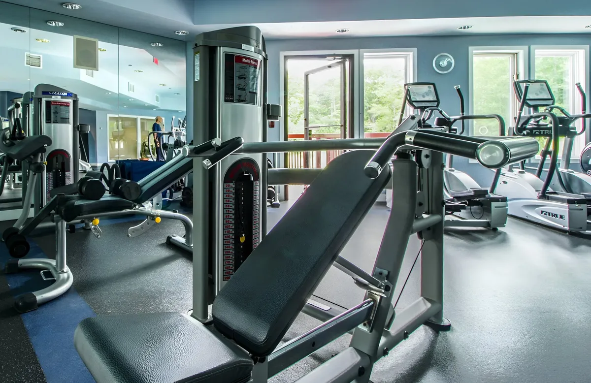 A bright, modern fitness center equipped with a weight bench, exercise machines, and large windows that let in natural light. The space is organized and welcoming, providing an energetic yet relaxing environment for guests to maintain their fitness routines while on vacation.
