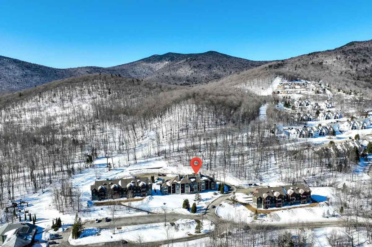 This scene shows snow-covered mountains behind a townhouse complex, complemented by green landscaping. It suggests a location immersed in nature where hiking, skiing, and exploring local wildlife are all possible.