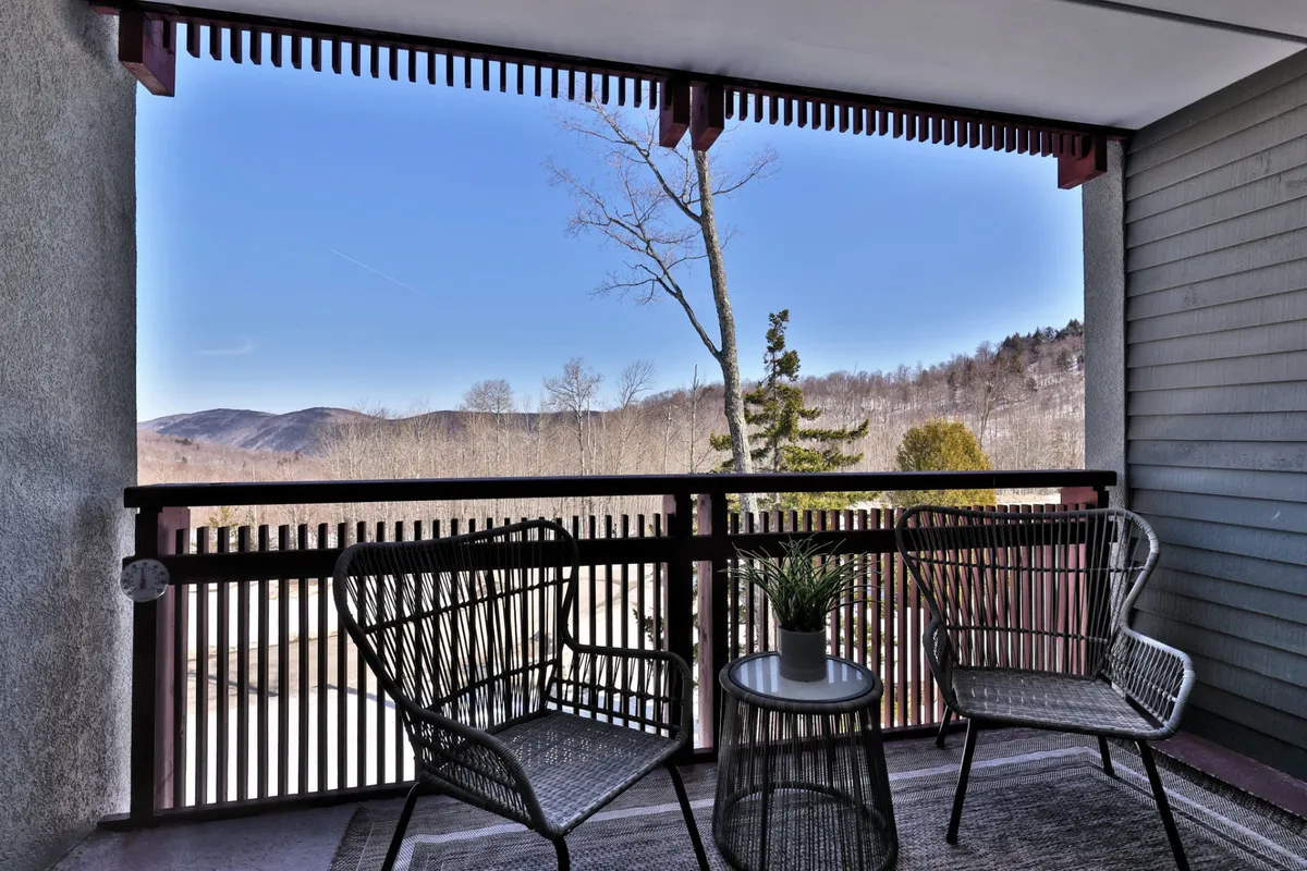 A private balcony with comfortable seating and potted plants overlooks a breathtaking mountain panorama. The serene setting invites moments of quiet reflection, morning coffee, or sunset views, reinforcing the seamless blend of indoor comfort and outdoor beauty.