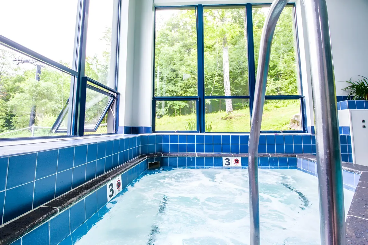 A serene hot tub area with blue tiles, large windows framing scenic views, and relaxed lighting, ideal for post-ski soaks or social wellness moments. This tranquil space embodies the calming, restorative side of resort life.